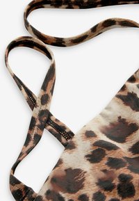 Top a halter con stampa leopardata caratterizzato da sottili spalline incrociate, tessuto liscio con una leggera lucentezza e una finitura texture nei toni di marrone e nero.