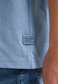 Světle modré bavlněné tričko s prošitým lemem, na boku se značkou "Petrol Ind". Texturovaná tkanina, casual design.