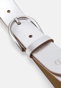 Ceinture métallique argentée avec une finition lisse, dotée d'une boucle circulaire en métal et de plusieurs trous de réglage sur un dos en cuir marron.