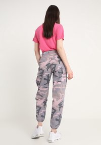 Rosa kortärmad skjorta i kombination med högmidjade cargobyxor i rosa och grå camouflage, med elastiska muddarna och sidofickor.