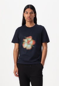 Tamsiai mėlynas medvilninis marškinėliai su išplautu gėlių grafiku ir užrašu "LYLE AND SCOTT" centre, trumpomis rankovėmis ir apvaliu kaklu.