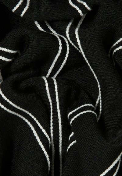 Tela de punto negra con rayas verticales y diagonales blancas, mostrando textura y pliegues en el material.