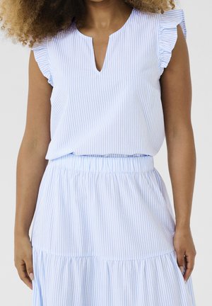 Mujer vestida con un top sin mangas de rayas verticales en azul claro y blanco con hombros con volantes y falda a juego.