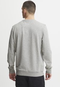 Gray sweatshirt made of soft fabric, featuring a round neck and long sleeves with ribbed cuffs. Simple design without visible logos.
