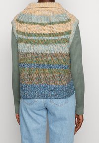 Paskiowany dzianinowy bezrękawnik w pastelowych kolorach niebieskiego, zielonego i pomarańczowego; teksturowana przędza; otwarty fason z kołnierzem typu szalowego i bez rękawów.