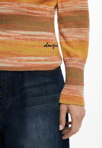 Stickad tröja med orange, gul och beige randning samt ribbade muddar. Broderad "Leisure" detalj nederst till vänster. Bärs med mörk denim.