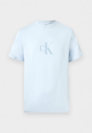 Lyseblå T-shirt med korte ærmer og rund halsudskæring med "cK"-logo trykt i stribet design centreret på brystet.