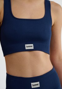 Marinblå ribbad kort topp med fyrkantig halsringning. Har en logotypetikett på midjebandet. Gjord av stretchigt tyg för komfort.