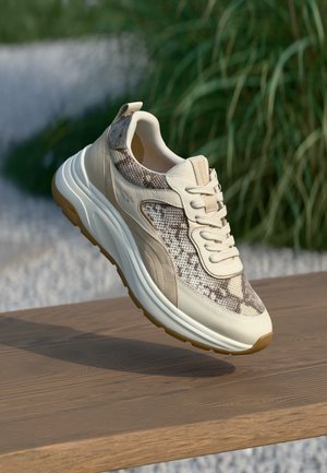 Μπεζ αθλητικά παπούτσια με υφή από σχέδιο φιδιού, από πλέγμα και δέρμα, χοντρή λευκή σόλα και λουράκι στο πίσω μέρος.