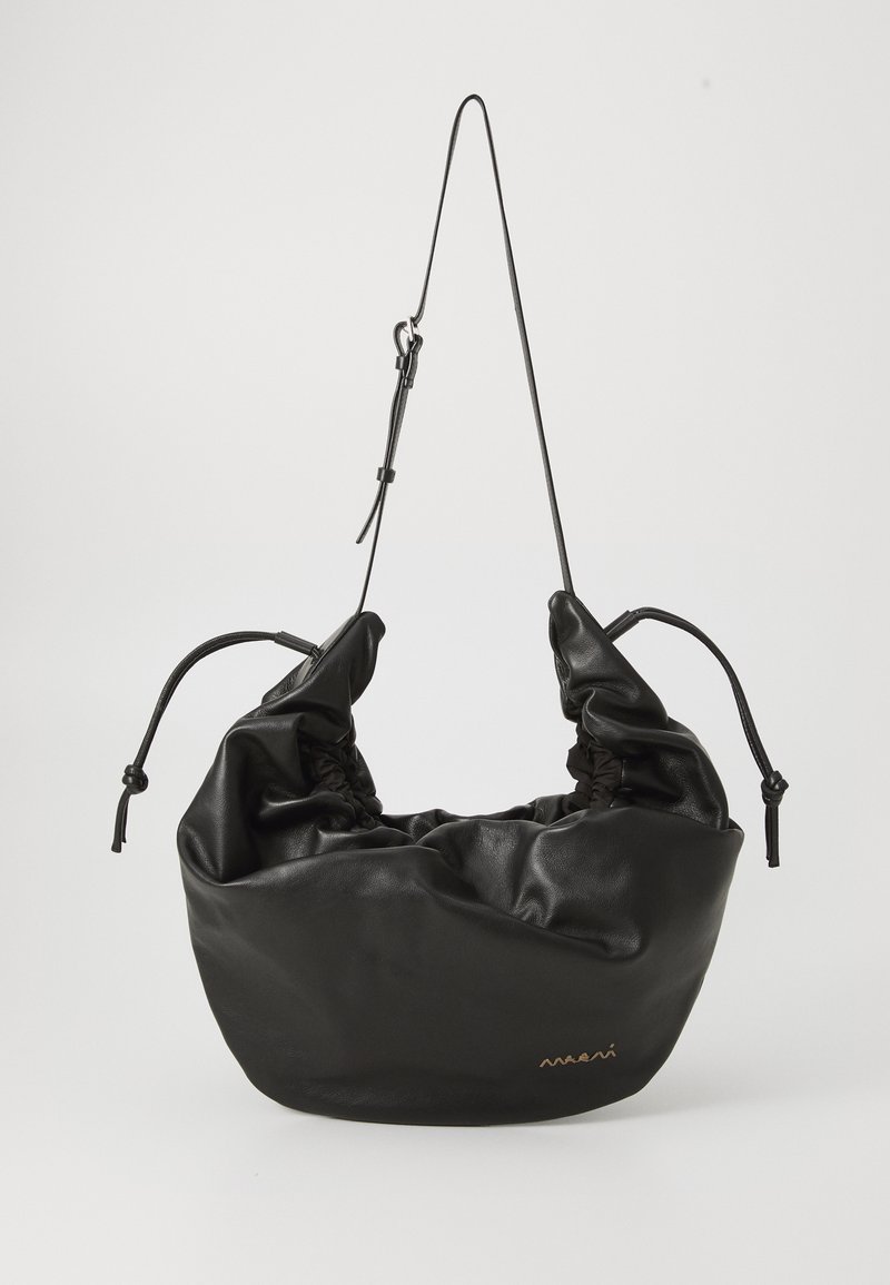 Juodas odinis krepšys su minkštu, susiraukšlėjusiu dizainu. Yra virvutės užsegimas ir ilgas, reguliuojamas diržas. Mažas prekės ženklo detalė priekyje.