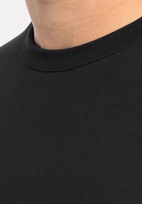 Camiseta negra de manga corta con cuello redondo y textura suave y lisa. La tela parece ligera y ligeramente elástica.