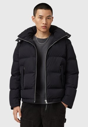 Black puffer jacket with a high collar, zip closure, and side pockets. Features quilted texture and a sleek, modern design.