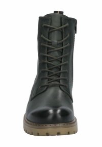 Botte en cuir vert foncé, avec un bout rond, un laçage avant, et une semelle en caoutchouc beige avec un motif cranté. Détail de fermeture éclair sur le côté.