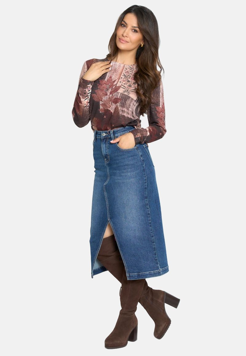 Blusa de manga larga con un estampado floral en tonos marrones, combinada con una falda de mezclilla de tiro alto y botas de tacón altas de color marrón.