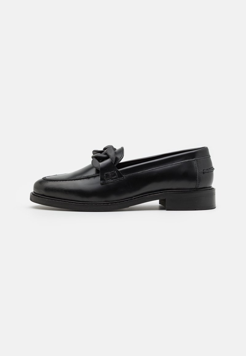 Zwarte leren loafers met een strikaccent, ronde neus, lage gestapelde hak en gestikte details langs de zijkanten. Glad textuur.