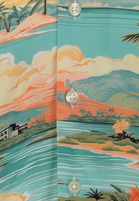 Tissu turquoise avec un imprimé de paysage tropical comprenant des palmiers, des collines, de l'eau et des boutons blancs le long d'une couture.