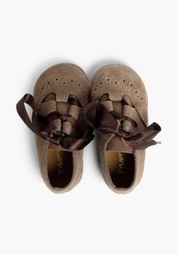 Zapatos de ante marrón con perforaciones decorativas y un diseño trenzado. Presentan cintas de satén marrón para el cordón. Textura suave y forma redondeada.