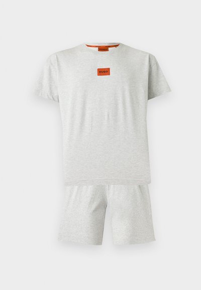 Ensemble T-shirt à manches courtes gris clair et short assorti avec un petit patch orange affichant "HUGO" sur la poitrine.