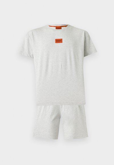 Ensemble T-shirt à manches courtes gris clair et short assorti avec un petit patch orange affichant "HUGO" sur la poitrine.