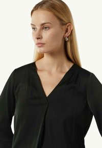 Schwarze V-Ausschnitt-Bluse mit langen Ärmeln, glatter Textur und minimalistischem Design. Verfügt über eine dezente Nahtdetails am Ausschnitt.
