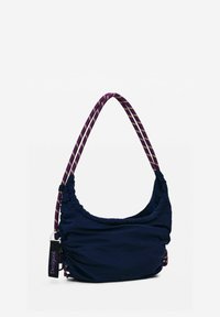 Marineblaue Stofftasche mit runder Form, versehen mit einem gerafften Design. Akzentuiert mit einem lila-weißen gestreiften Griff und einem Markenschild.