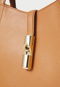 Sac à main en cuir tan avec une surface texturée. Il est doté d'une fermeture en métal doré et d'accents en cuir lisse.