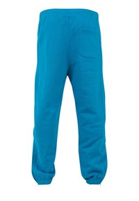 Pantaloni sportivi turcoaz cu talie elastică, croială slim fit și un singur buzunar la spate. Mansetele sunt conice cu un finisaj elastic.