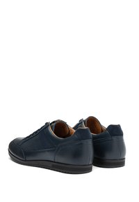 Námornícke kožené tenisky s textúrovaným povrchom, semišovými akcentmi a gumovými podrážkami. Obsahujú šnurovací systém a hnedú vnútornú podšívku.