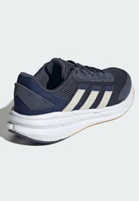 Granatowe buty do biegania z siateczkową cholewką, jasnoszarymi akcentami i trzema charakterystycznymi paskami. Posiadają amortyzowaną podeszwę dla lepszego wsparcia.