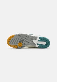 Sole obuvi New Balance obsahuje kombinaci šedé gumy s tyrkysovými a oranžovými detaily, texturovaná pro záběr a stabilitu, navržena pro výkon.