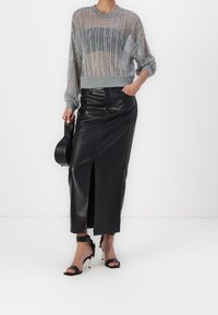 Szary, fakturowany, dziergany sweter z okrągłym dekoltem, połączony z czarną skórzaną ołówkową spódnicą z bocznym rozcięciem. Całość uzupełniają czarne sandały na obcasie.