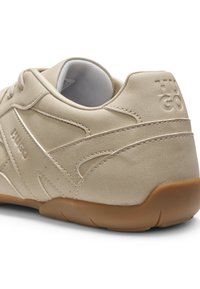 Beiger Sneaker mit glattem, synthetischem Obermaterial, strukturierten Akzenten und Gummisohle. Verfügt über dezentes Branding an der Ferse und gestickte Details.