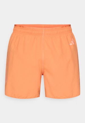 Svetlooranžové športové šortky s elastickým pásom a jemným nápisom "RUNNING" navrchu. Majú hladkú textúru a orezaný spodný okraj.