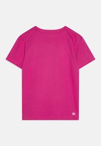 T-shirt en coton fuchsia à manches courtes, avec un col rond et une étiquette "ULTRA SEC" au bas. Texture lisse avec un design de couleur unie.