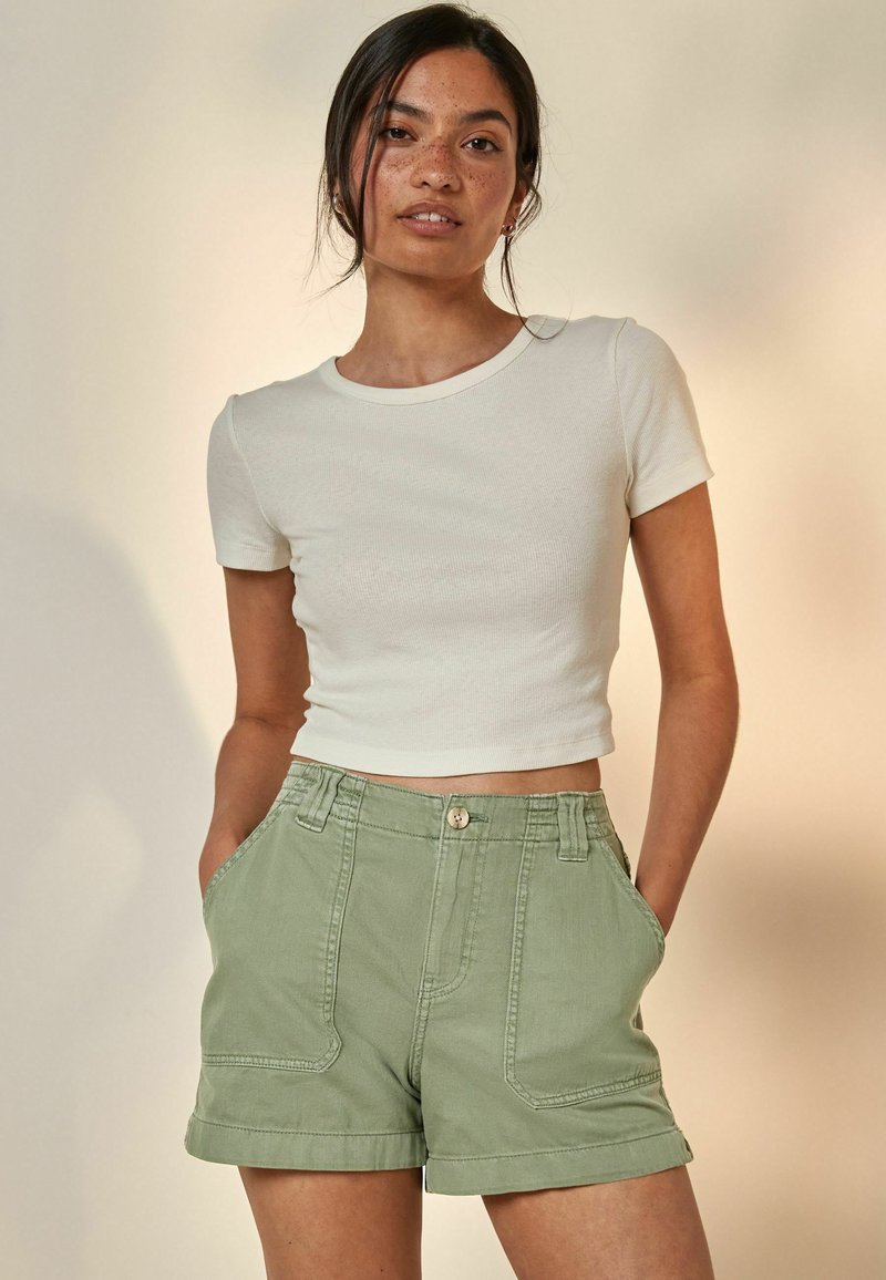 Vitt randigt kortärmat t-shirt parat med högmidjade mintgröna shorts med framfickor och synliga sömdetaljer.