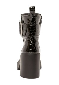 Bottine noire en simili-crocodile avec un talon épais, présentant un détail de boucle sur le côté et une languette à l'arrière. Fini lisse et brillant.