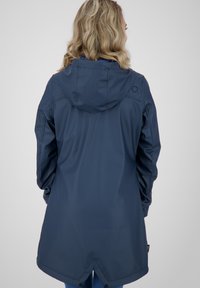 Granatowa wodoodporna kurtka z kapturem, z długimi rękawami, zwężaną talią i zaokrąglonym tylnym dołem. Gładkie, matowe wykończenie, minimalne detale.