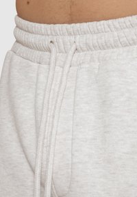 Hellgraue Jogginghosen mit elastischem Bund und Kordelzug. Weicher, strukturierten Stoff mit lockerer Passform und Seitentaschen.