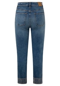 Blå denimjeans med broderade blommönster på fållen, bakfickorna och en brun läderlapp på midjebandet.