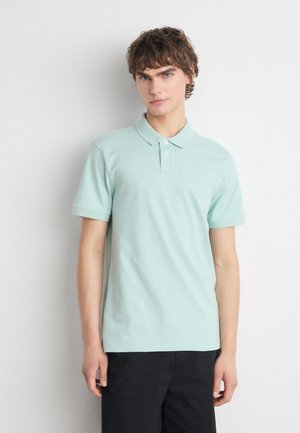 Polo mint vert en coton doux, avec une patte de boutonnage à deux boutons, des manches courtes et un petit logo sur la poitrine.