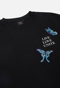 Zwarte katoenen t-shirt met blauwe en turquoise vlindermotieven en de tekst "LEEF LIEFDE EENHEID" in het wit. Ronde halslijn en korte mouwen.