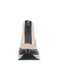 Bottes avec un design en suède beige et en verni noir, dotées d'une fermeture zippée et d'une semelle rayée blanche. La vue de face met en avant la silhouette.