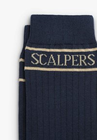 Dunkelblaue gerippte Socken mit einem kontrastierenden cremefarbenen Band, auf dem der Text "SCALPERS" steht. Aus weichem Strickmaterial mit elastischem Bund.