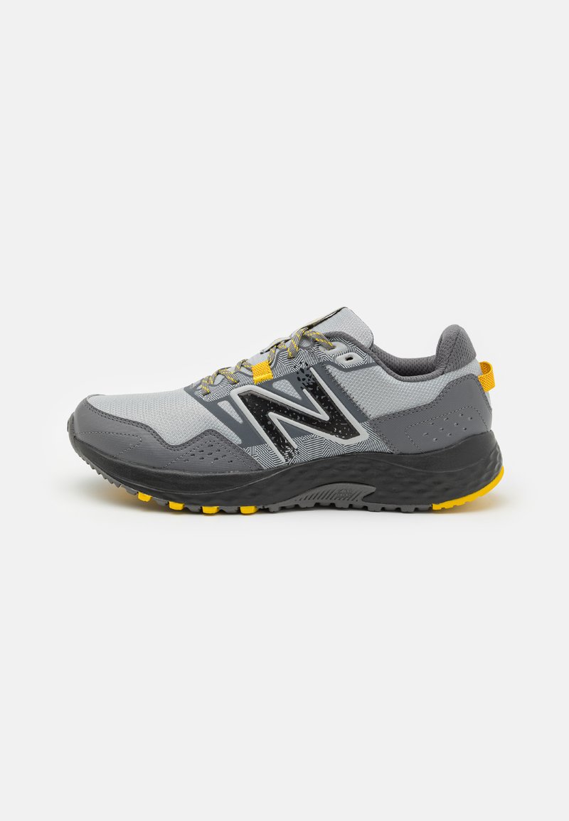 Gray athletic shoe with a textured gray mesh upper, black accents, yellow laces, and a grip sole featuring yellow studs.