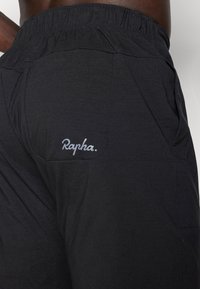 Fekete sort könnyű anyagból, laza derékkal és egy hátizsebbel, amelyen a "Rapha." logó szürke színben található. Egyszerű és funkcionális dizájn.