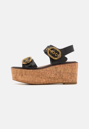 Sandalias negras de plataforma con cuña de corcho, que cuentan con una hebilla decorativa dorada y un diseño de correas. Textura de cuero suave.