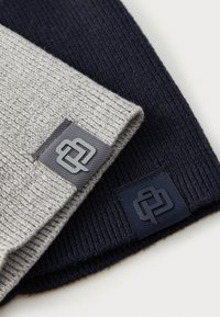 Two beanie hats; one in light grey with a ribbed texture and a grey logo tag, the other in dark navy with a similar ribbed texture and tag.