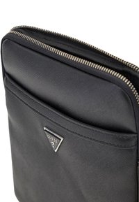 Pochette en simili cuir noir avec fermeture éclair argentée, dotée d'une poche avant et d'un accent logo triangulaire. Finition lisse et texturée.
