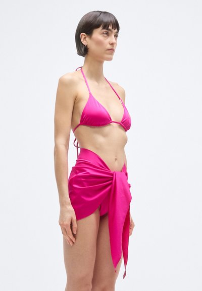 Világos rózsaszín háromszög felsővel rendelkező bikini, vékony pántokkal. Hozzáillő, deréknál megkötött szoknyával, puha textúrával.