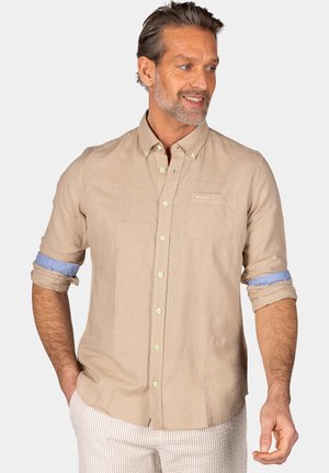 Lichtbeige overhemd met knopen in het groen, opgerolde mouwen die een blauwe accent tonen, en een borstzak met logodetail.